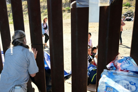 Migrants at the US-Mexico border wall.