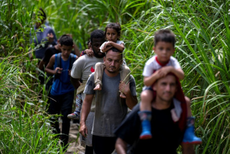 Migrants carrying children walk by the jungle near Bajo Chiquito 