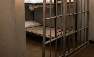 A Bunk Bed With Striped Linen Behind Bars