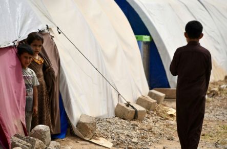 Children stand by tents at the Al-Jadaa camp