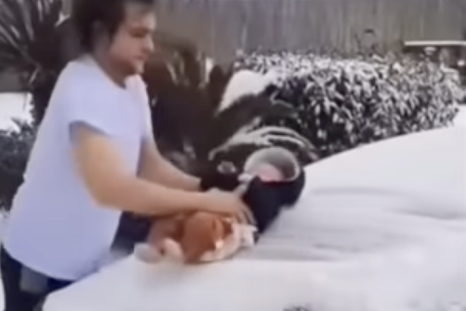 Man uses baby to wipe snow off of windshield