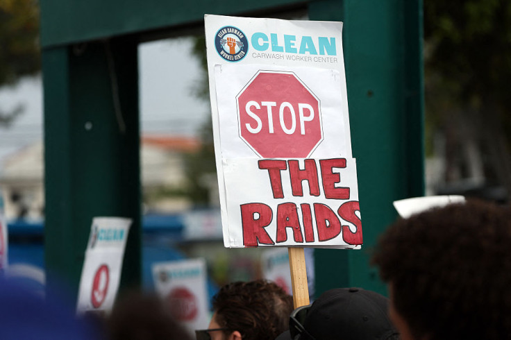 People hold signs to urge the end of immigration raids