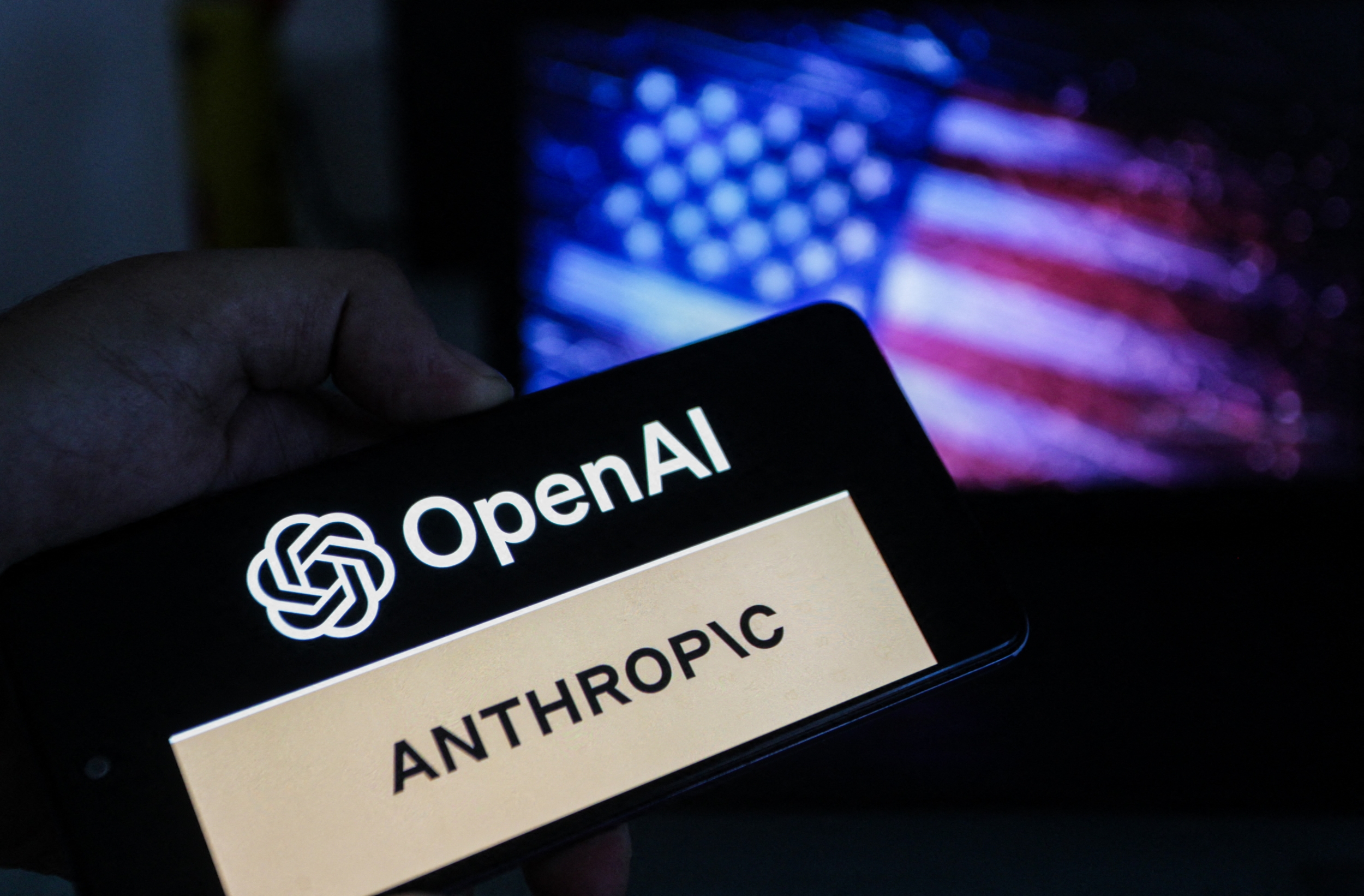 A smartphone screen displays the logos of OpenAI and Anthropic against a blurred backdrop of the American flag, symbolizing the intensifying competition in artificial intelligence between the two US-based companies in Tunis,Tunisia on June 17,2026. Photo by Imen Ben Youssef / Hans Lucas / AFP via Getty Images